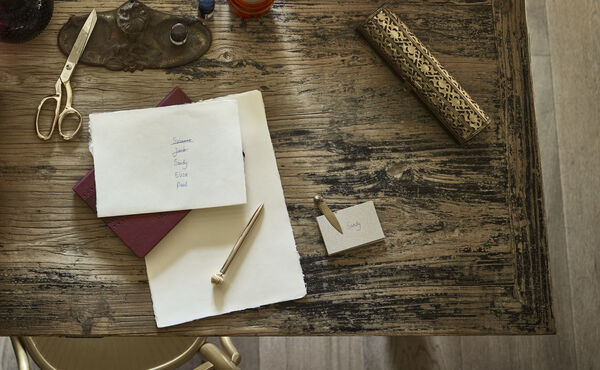 Ferieplanlægningsliste og bordkort på et rustikt skrivebord – en mindful tilgang til at reducere sæsonbestemt stress og holde orden.